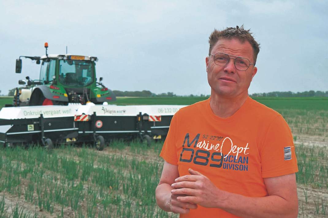 Akkerbouwer Dirk Gesink in het veld met op de achtergrond een machine.