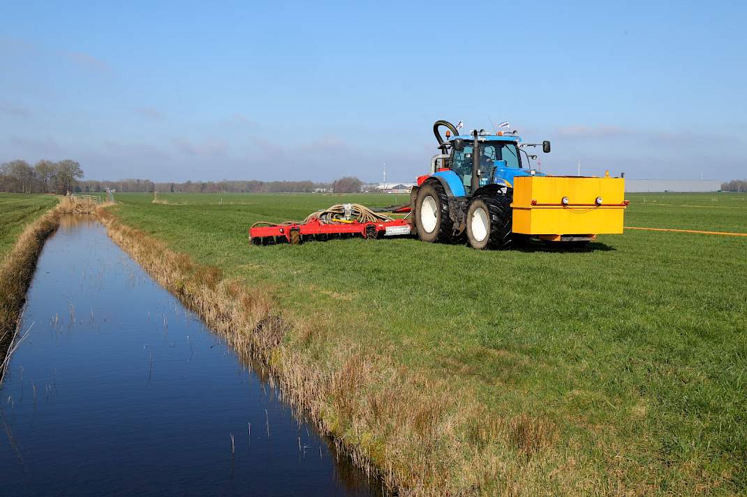 Boer rijdt mest uit langs sloot