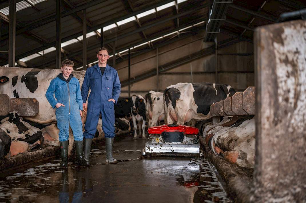 Twee melkveehouders in een stal voor een Discovery Collector mestrobot