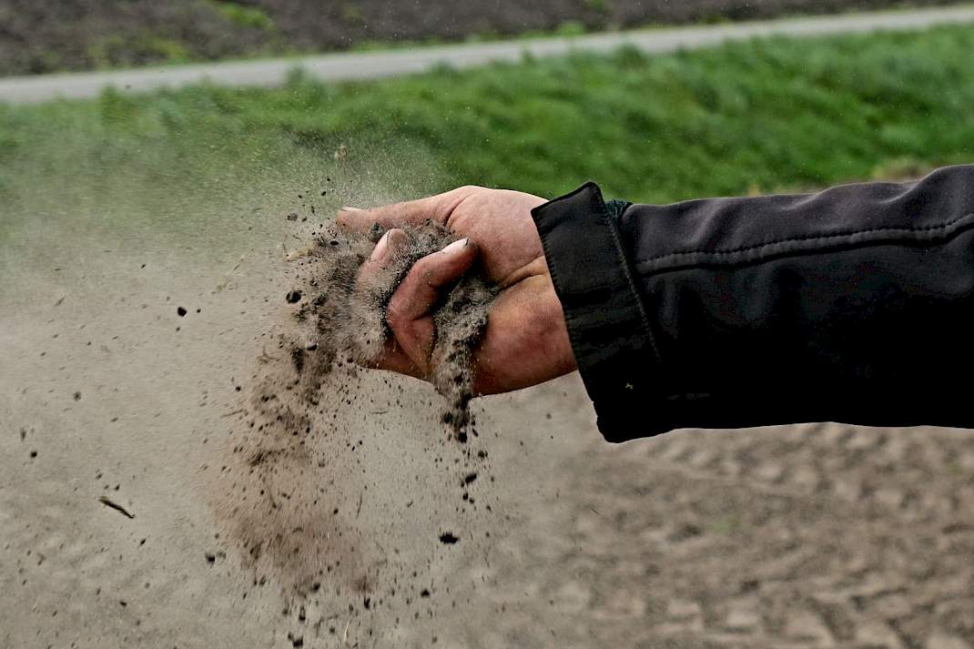 Een boer laat grond door de hand gaan