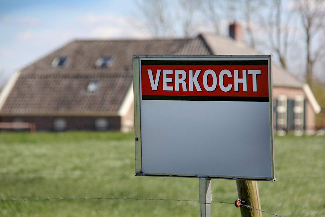 Een makelaarsbord bij een boerderij