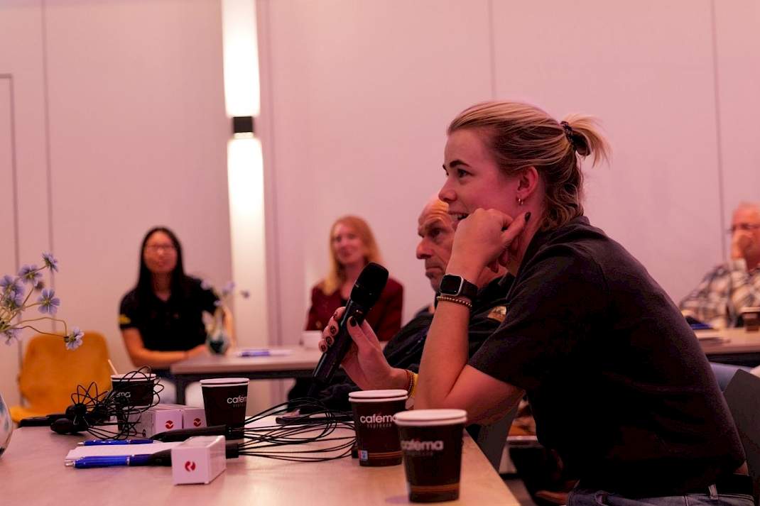 Bezoeker aan het woord met microfoon tijdens de paneldiscussie over vaccinatie van leghennen en vogelgriep